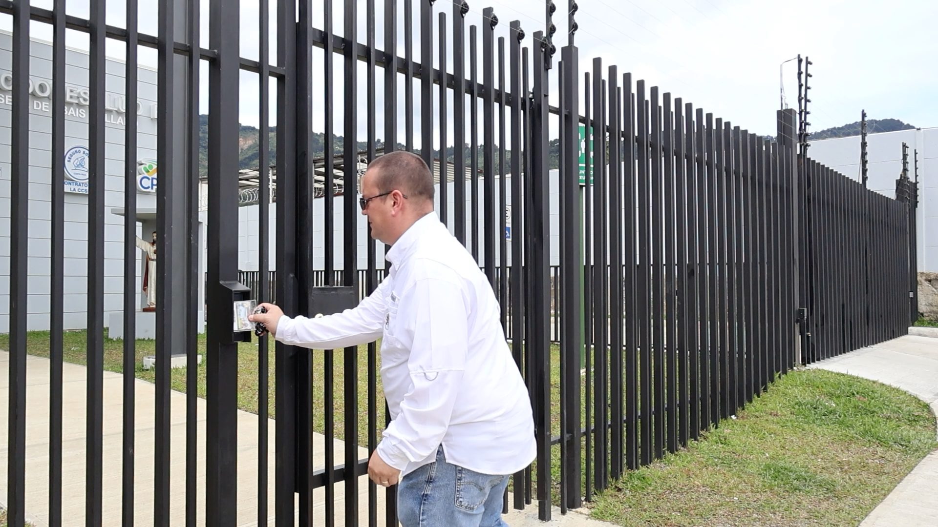 Hombre adulto ingresando por un portón peatonal con lector de tags y cerradura electromagnética en la entrada del EBAIS de El Llano administrado por COOPESALUD.