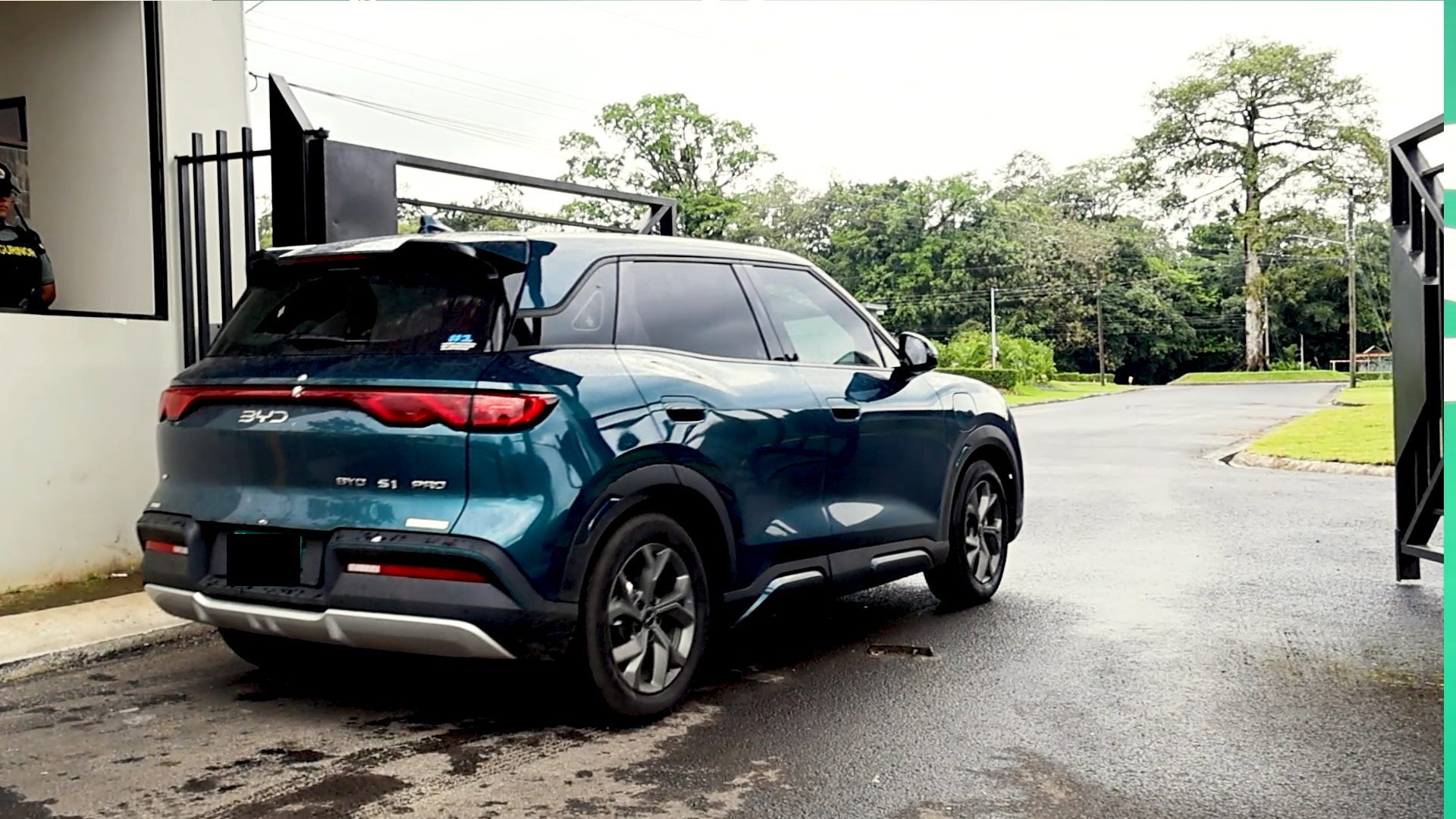 Vehículo tipo eléctrico marca BYD entrando en un condominio con portones de barrotes abatibles.