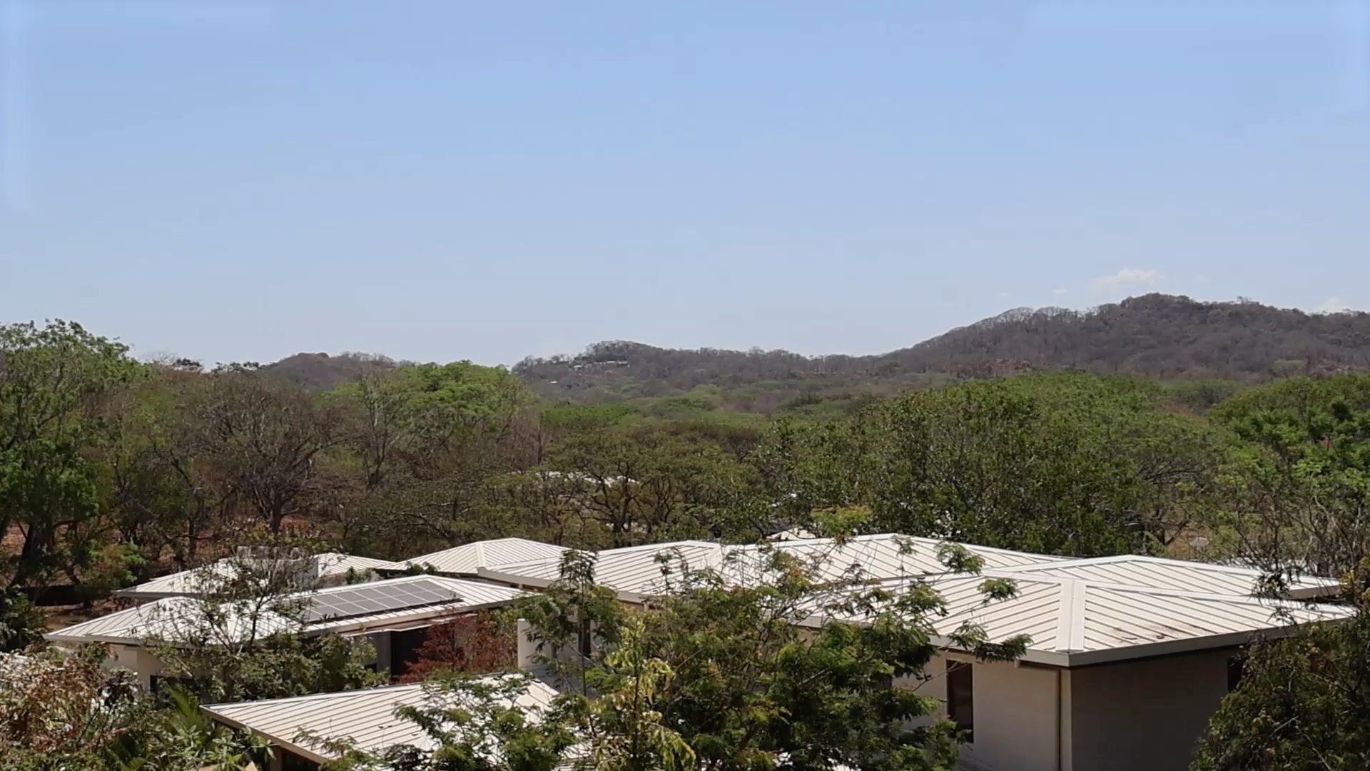 Paisaje aéreo de tamarindo park donde se observan techos de viviendas combinados con arboles y al fondo una serie de montañas.